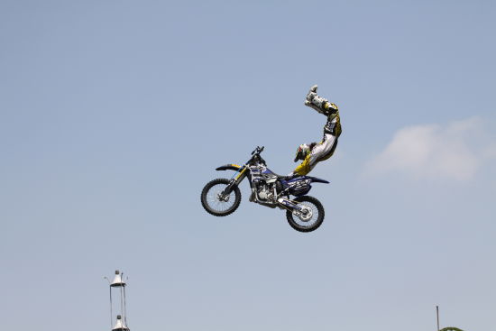 图为摩托车手在高空腾跃时表演倒立，绝活博得满堂彩。