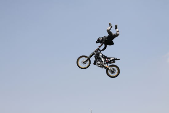 世界极限运动大赛亚洲站在江湾体育中心举行，图为车手在摩托上倒立，此时摩托车跃起约有十余米高